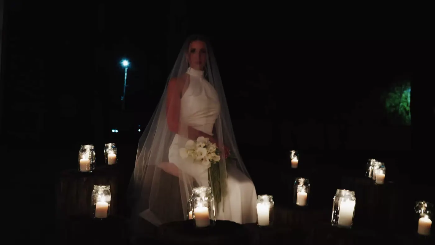 Panna młoda w welonie siedzi wśród świec, kadr z filmu ślubnego Miętowe Lato