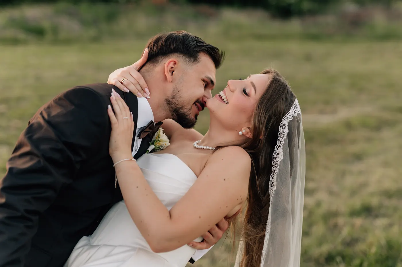 Para młoda śmieje się przytulona na łące w złotym świetle